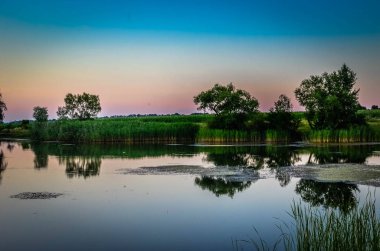 Yansımalar yeşil ağaçlar, mavi gökyüzü ve bulutlar sakin su göle