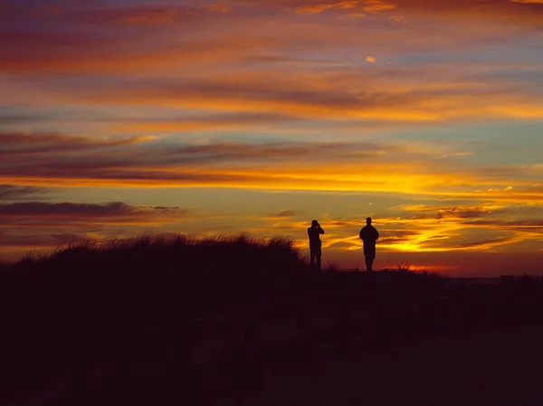 Silueta de gente mirando la playa del atardecer — Foto de Stock