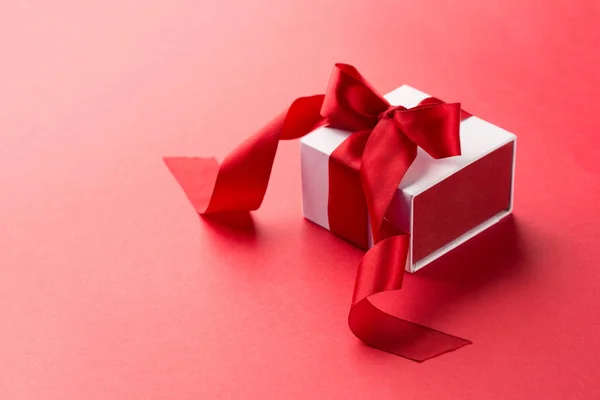 Scatola regalo bianca con nastro rosso su sfondo rosso — Foto Stock