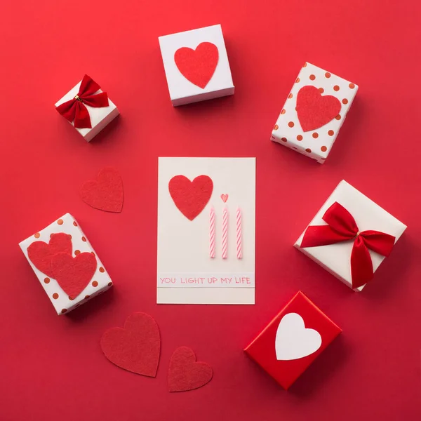 Χειροποίητα τυλιγμένα κουτιά δώρου, κόκκινες καρδιές και κεριά, κόκκινο πίσω μέρος — Φωτογραφία Αρχείου