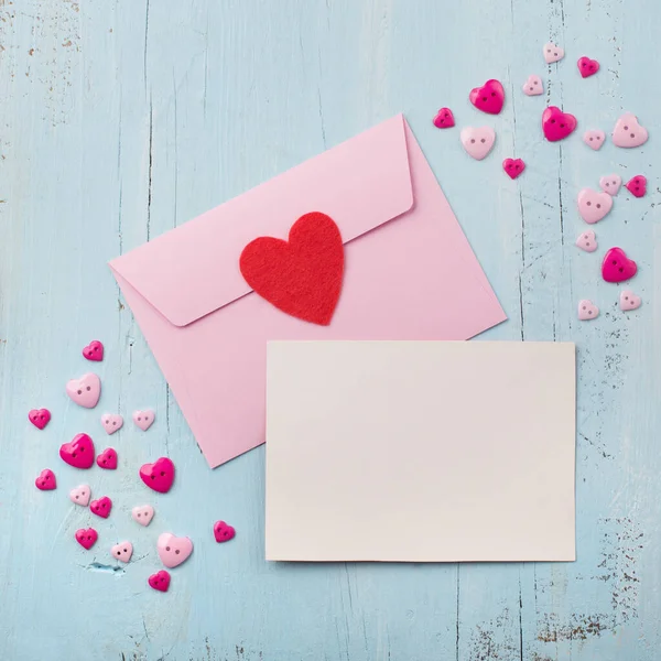 Розовый конверт с пустой бумагой и красным сердцем — стоковое фото