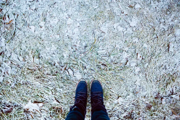 脚踏在靴子里。 草上的第一场雪。 冬天。 冷冰冰 — 图库照片