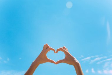 Mavi gökyüzüne karşı el yapımı kalp şekli Eller kadın
