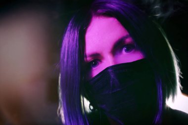 Maskeli genç bir kadın. Evde izolasyon koruması var. Coronavirus. Pembe renk