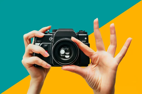 Vintage Camera in female hand. A photo. Photographer. Manual focus. Colored background. Persian Green and Sunshade