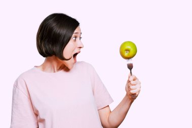 Genç kadın elinde yeşil elmalı bir çatal tutuyor. Diyet yapan kadın konsepti için sağlıklı organik gıda