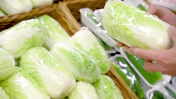 男はスーパーマーケットで緑の野菜レタスを選択 — ストック動画