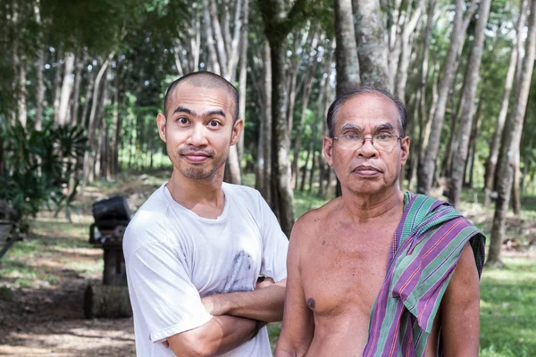 Tailandés anciano jardinero hombre con hijo de pie en huerto árbol de goma — Foto de Stock