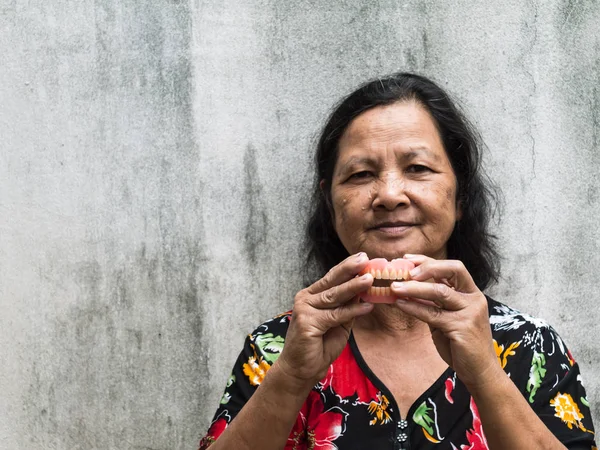 Velho tailandês mulher segurando dentes falsos — Fotografia de Stock