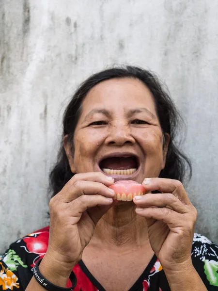 Viejo tailandés mujer retrato abierto monte y celebración de dientes falsos — Foto de Stock