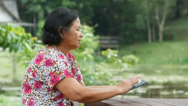 Tailandês mulher sênior usando tablet no jardim — Vídeo de Stock