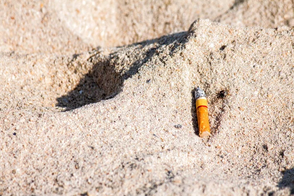 Mozzicone di sigaretta sulla spiaggia di sabbia — Foto Stock