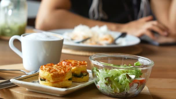 集食物 烤菠菜与乳酪和咖啡在木飞碟与顾客的散焦在背景下 — 图库视频影像
