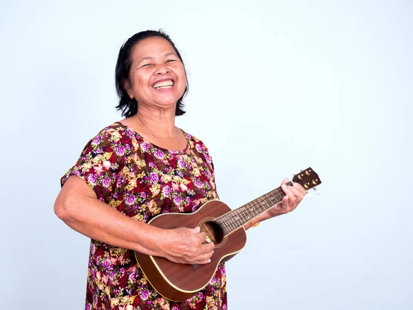 Asian senoir woman playing ukulele with big smile — Stock Photo, Image