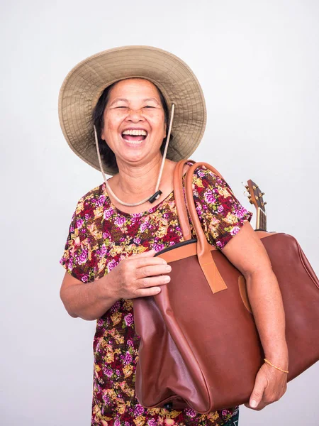 Senoir 女人带着四弦琴和棕色大袋在白色背景下大笑 — 图库照片