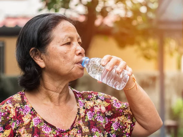 公園でボトルから水を飲む高齢者アジア女性 — ストック写真