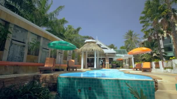 青い空 タイの下でヤシの木やビーチの景色を望む高級リゾートやホテルでスイミングプール パンニングショット — ストック動画