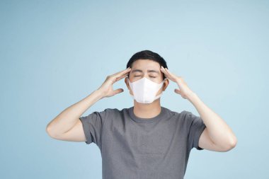 Grip maskeli Asyalı genç adam korona virüsü salgınına karşı ya da kış boyunca grip veya soğuk algınlığını önlüyor.