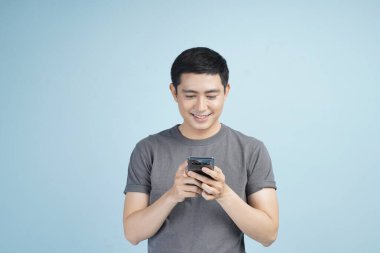 Kredi kartıyla alışveriş yapan genç Asyalı bir adam. Stüdyodaki izole gri arka planda bir şeyler alıp satıyor.