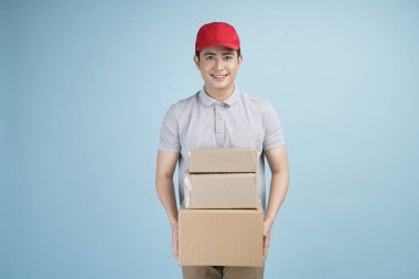 Karton kutu taşıyan ve kameraya gülümseyen genç bir Asyalı. Üniformalı, karton kutu taşıyan genç adam.