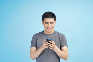 Kredi kartıyla alışveriş yapan genç Asyalı bir adam. Stüdyodaki izole gri arka planda bir şeyler alıp satıyor.