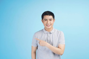 Kredi kartıyla alışveriş yapan genç Asyalı bir adam. Stüdyodaki izole gri arka planda bir şeyler alıp satıyor.