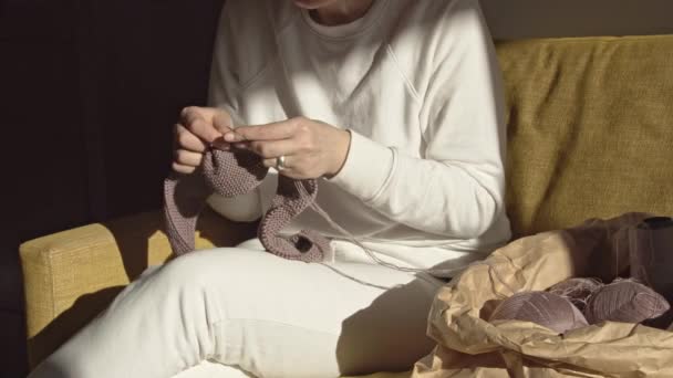 Woman knitting needles on the couch on a sunny day — Stock Video