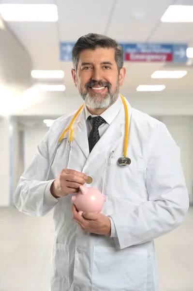 Médico hispano colocando monedas en Piggy Bank —  Fotos de Stock