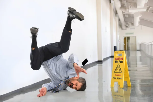 オフィスビル内の湿った床に倒れる上級実業家 ストック写真