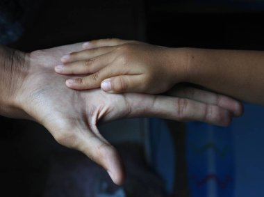 Korunmanın sembolü olarak yetişkinlerin ve çocukların elleri.