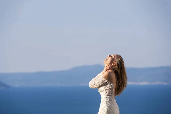 Porträt der schönen Braut, die an der Küste entlang geht und ein wunderschönes weißes Brautkleid trägt — Stockfoto