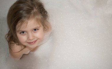 Mutlu gülümseyen küçük kız bir banyo ile tam köpük oturuyor