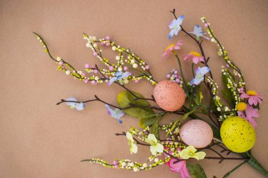 Paskalya Paskalya yumurtaları ve bahar çiçekleri ile arka plan. Kraft kağıt üzerinde kopya alanı ile Üstten Görünüm.