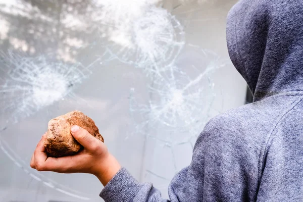 El niño sostiene una piedra para tirarla contra un vaso y romper un viento — Foto de Stock