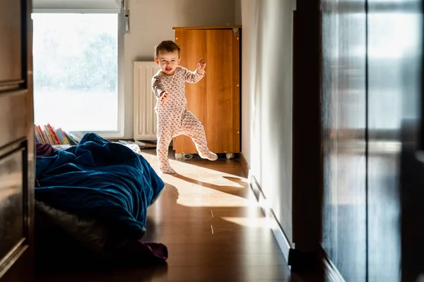 Bebê recém-acordado de pijama dá seus primeiros passos no quarto — Fotografia de Stock