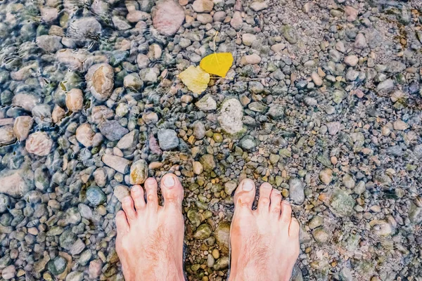 Bare feet cooling off in a stream full of pebbles, revitalizing
