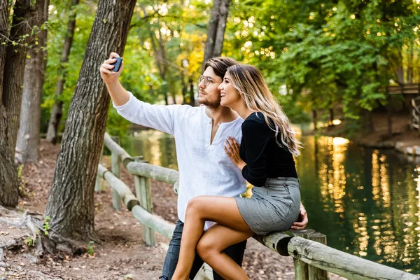 Enamorados abrazándose mientras se toman una selfie entre risas — Foto de Stock