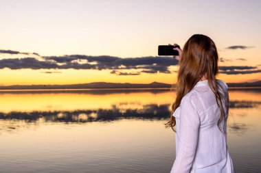 Genç bir kadın cep telefonuyla fotoğraf çekiyor.