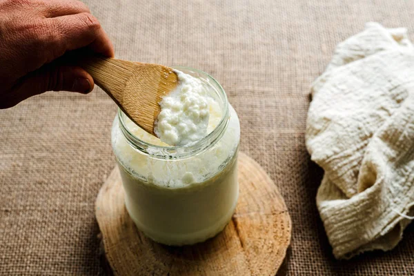 La mano dell'uomo versa il kefir di latte in una brocca per preparare un pane sano — Foto Stock