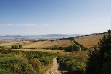 Yürüyüşçüler kutsal Santiago şehrine doğru kayalık bir yolda yürüyorlar, Spai.