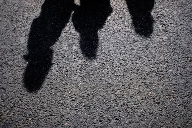 İnsanların gölgesinde asfalt bir siluet, sert bir ışık