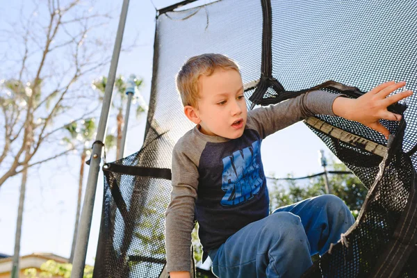 Günbatımında bir trambolin üzerinde bahar eğlenceli olan çocuğun. — Stok fotoğraf