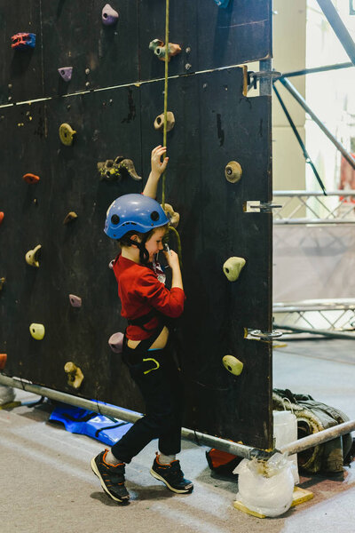 Child on the walls of a climbing wall with the help of a safety 