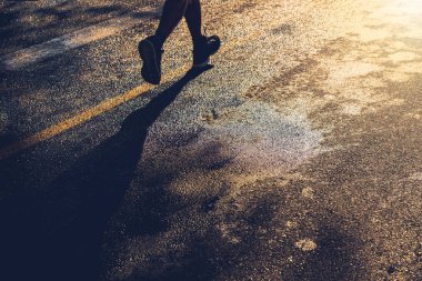 Islak asfalt üzerinde gün batımında yalnız bir koşucu çalışır, boşluğu kopyala.