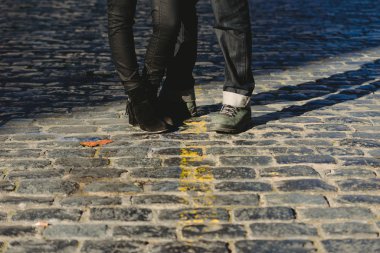Birbirine aşık bir çift, bir şehir sahnesinde kucaklaşıp, vücudunun alt kısmının fotoğrafını çekiyor.