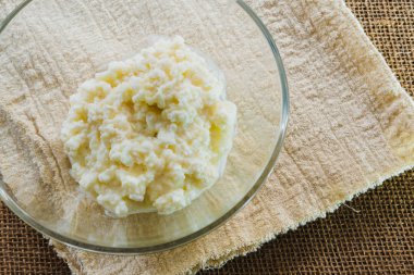 Kefir granülleri şeffaf bir kâse içinde, kırsal bir kumaş üzerinde, polis bezinde.