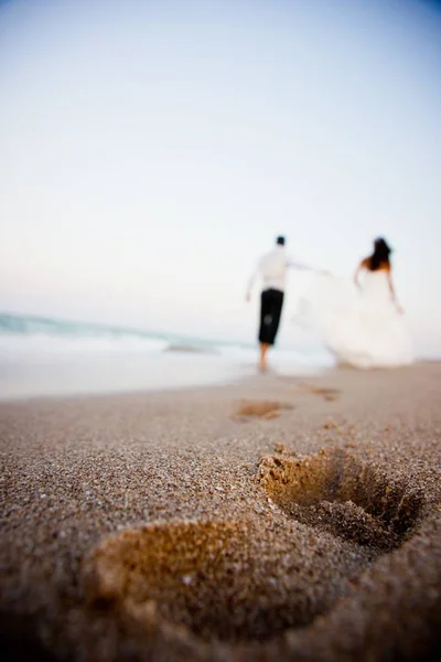 Casal de casamento desfocado no fundo andando ao longo da bea — Fotografia de Stock
