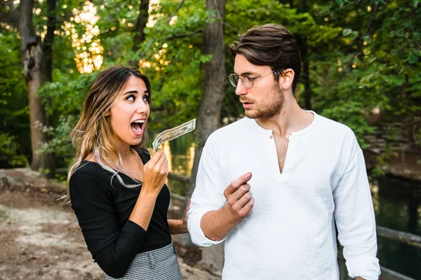 Frau stiehlt Mann einen Dollarschein aus der Hand. — Stockfoto