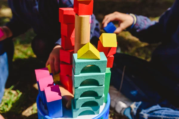 Niños con bloques de madera jugando ayudados por un adulto —  Fotos de Stock