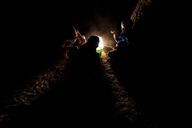 Bir grup çocuk, gece boyunca kum havuzunda oynuyorlar.
